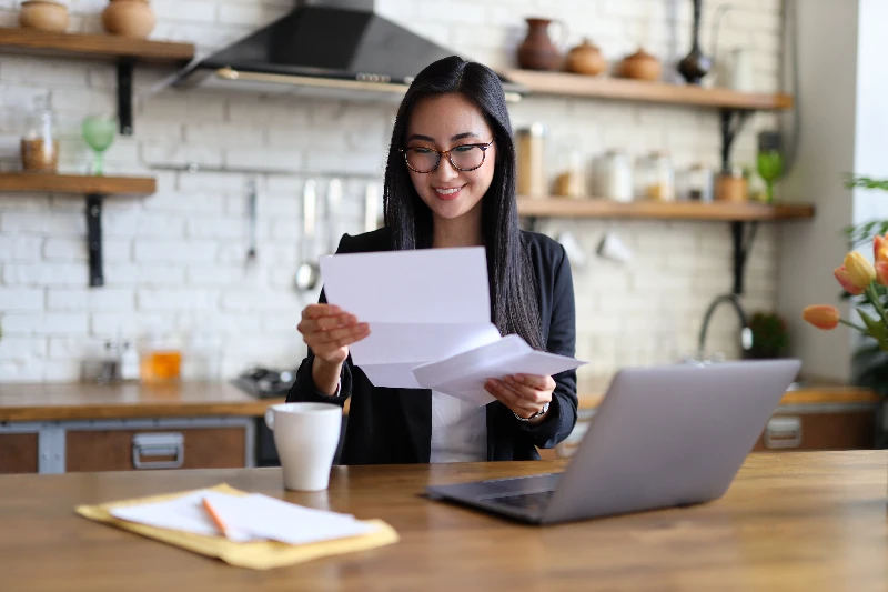 Wendy Hartman 3 Businesswoman happily reads financial letter at a desk with laptop