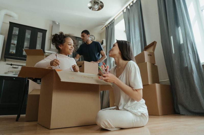 E.J. Gilbride 2 A joyful family unpacking boxes while moving into their new 1793120483